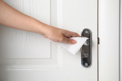 Photo of Woman using tissue paper to open door, closeup