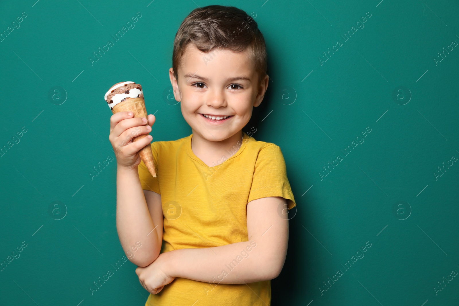 Photo of Adorable little boy with delicious ice cream against color background