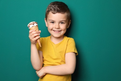 Photo of Adorable little boy with delicious ice cream against color background