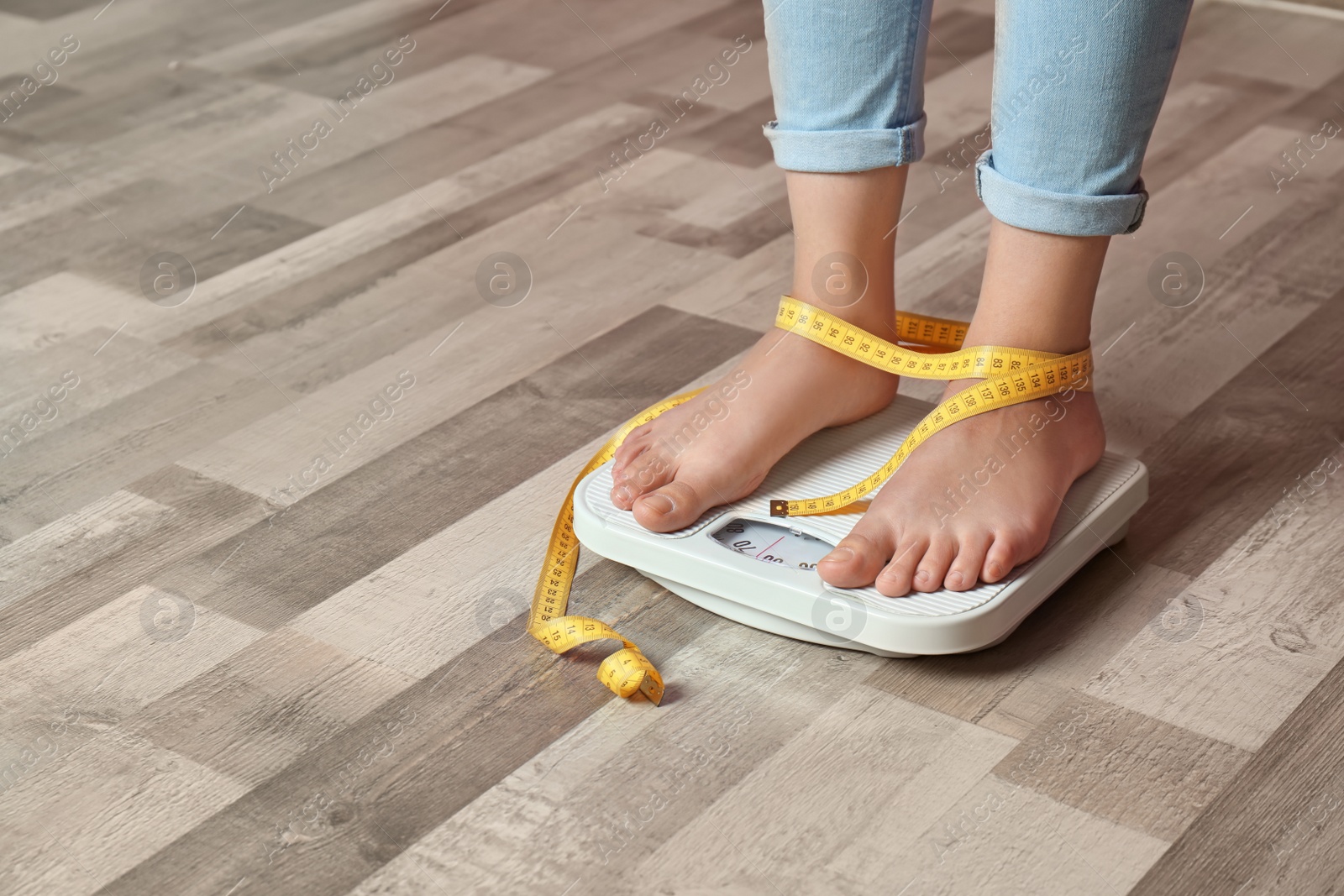 Photo of Woman with tied legs measuring her weight using scales on floor. Healthy diet