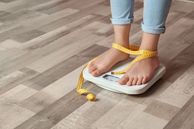 Woman with tied legs measuring her weight using scales on floor. Healthy diet