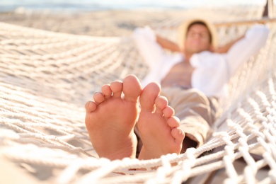 Man relaxing in hammock outdoors, focus on legs