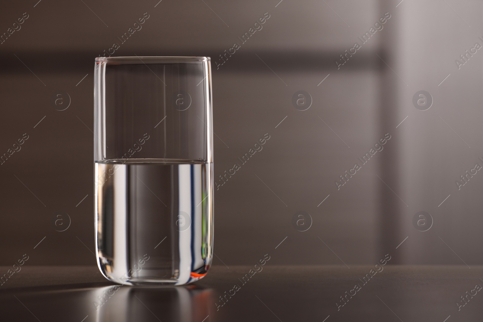 Photo of Glass of pure water on table against blurred background, space for text