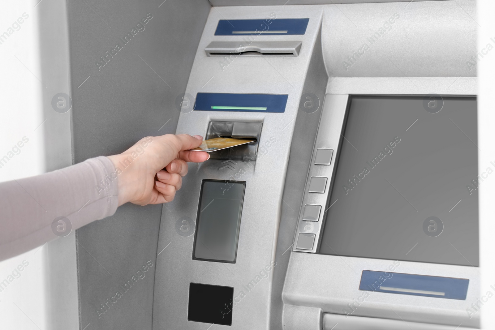 Photo of Woman inserting credit card into grey cash machine, closeup