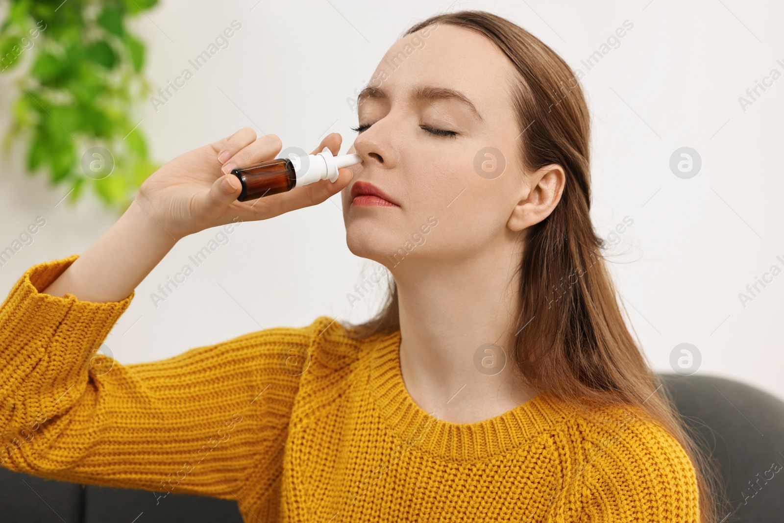 Photo of Medical drops. Young woman using nasal spray indoors