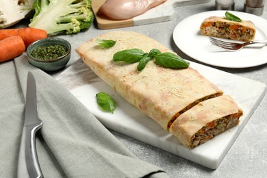 Photo of Delicious strudel with chicken, vegetables and basil served on grey table