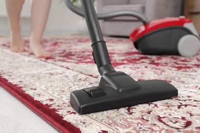 Photo of Woman cleaning carpet with vacuum cleaner at home, closeup