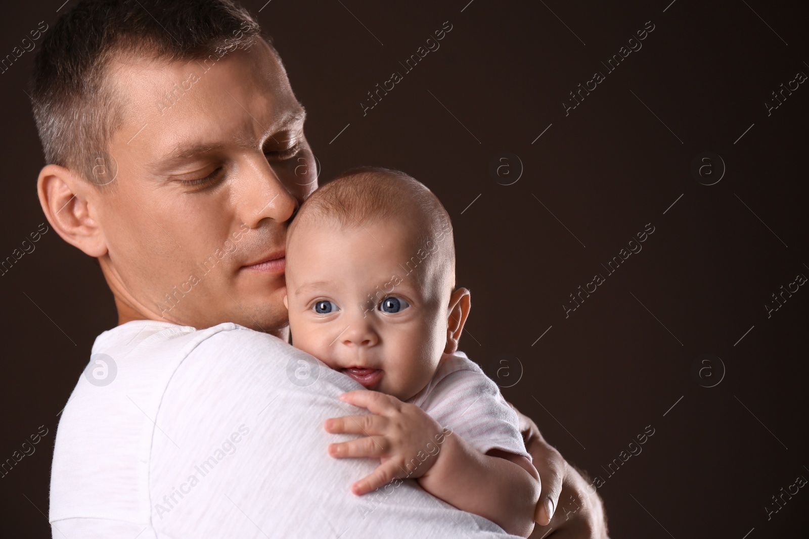 Photo of Happy father with his little baby on dark background. Space for text