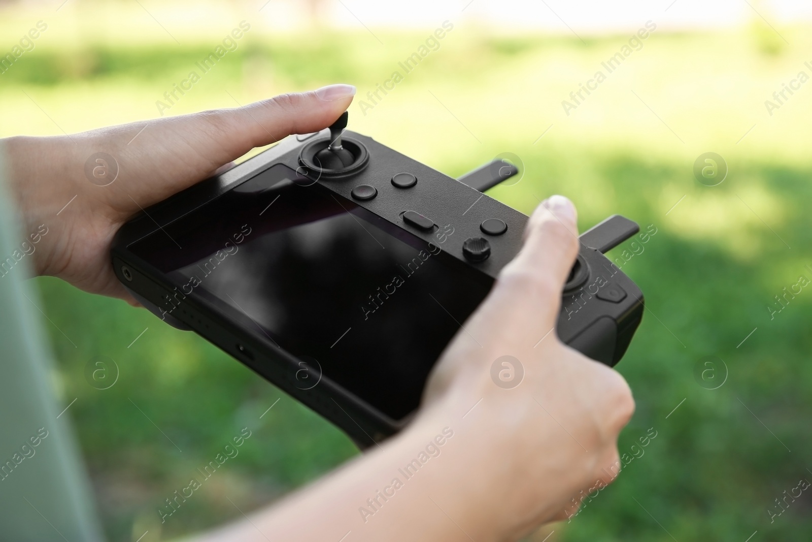 Photo of Woman holding new modern drone controller outdoors, closeup of hands