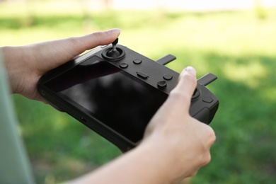 Photo of Woman holding new modern drone controller outdoors, closeup of hands