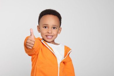 Photo of African-American boy showing thumb up on light grey background