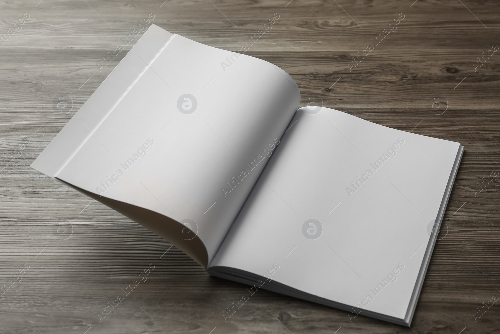 Photo of Open blank paper brochure on wooden table. Mockup for design