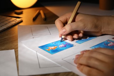 Photo of Woman drawing cartoon sketch in storyboard at workplace, closeup. Pre-production process