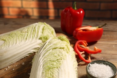 Photo of Fresh Chinese cabbages, bell peppers and salt on wooden table, closeup