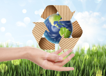 Image of Woman with illustration of Earth and recycling symbol in hand, closeup
