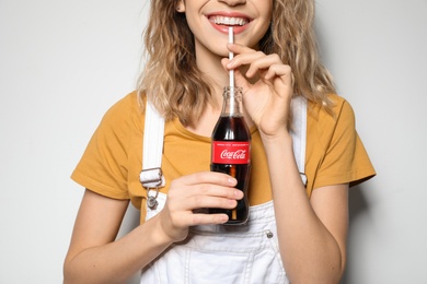 Photo of MYKOLAIV, UKRAINE - NOVEMBER 28, 2018: Young woman with bottle of Coca-Cola on white background, closeup