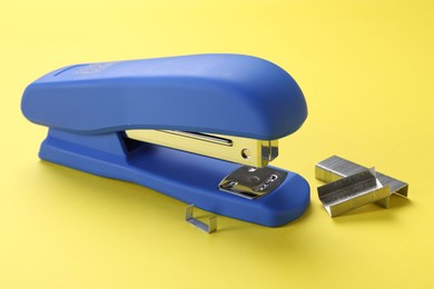 Photo of Blue stapler with staples on yellow background