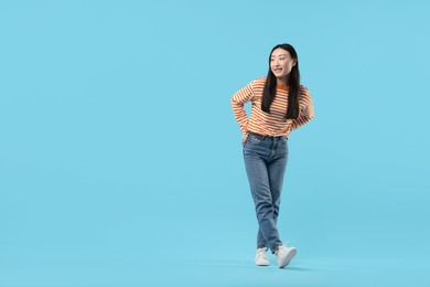 Photo of Full length portrait of smiling woman on light blue background. Space for text