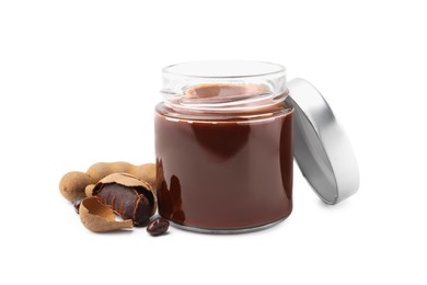 Photo of Jar of tasty tamarind sauce and fresh pods isolated on white