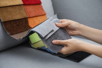 Photo of Woman choosing fabric among colorful samples on grey sofa, closeup