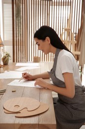 Photo of Young woman drawing with pencil at table indoors