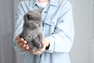 Photo of Woman with cute fluffy kitten indoors, closeup