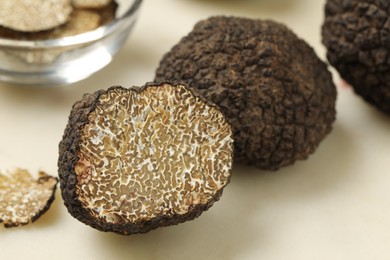 Photo of Whole and cut black truffles on light table, closeup