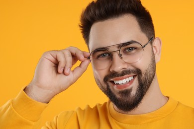 Photo of Handsome man wearing glasses on orange background