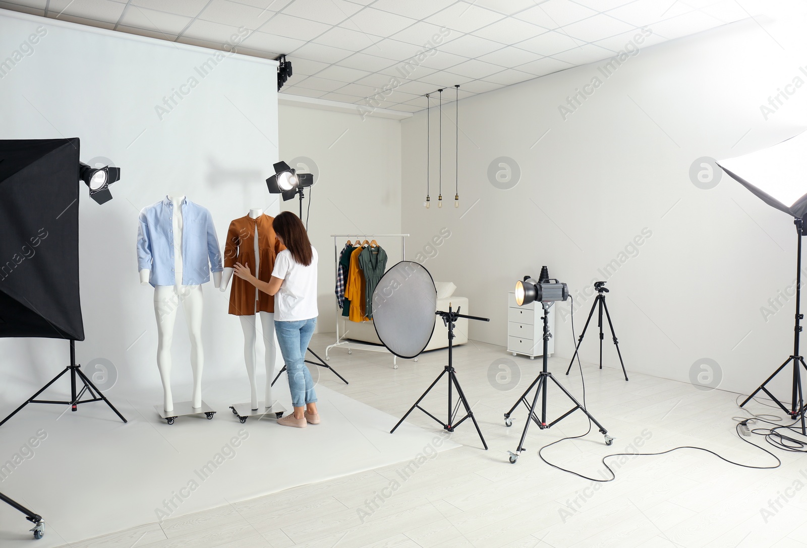 Photo of Woman putting clothes on ghost mannequins in professional photo studio