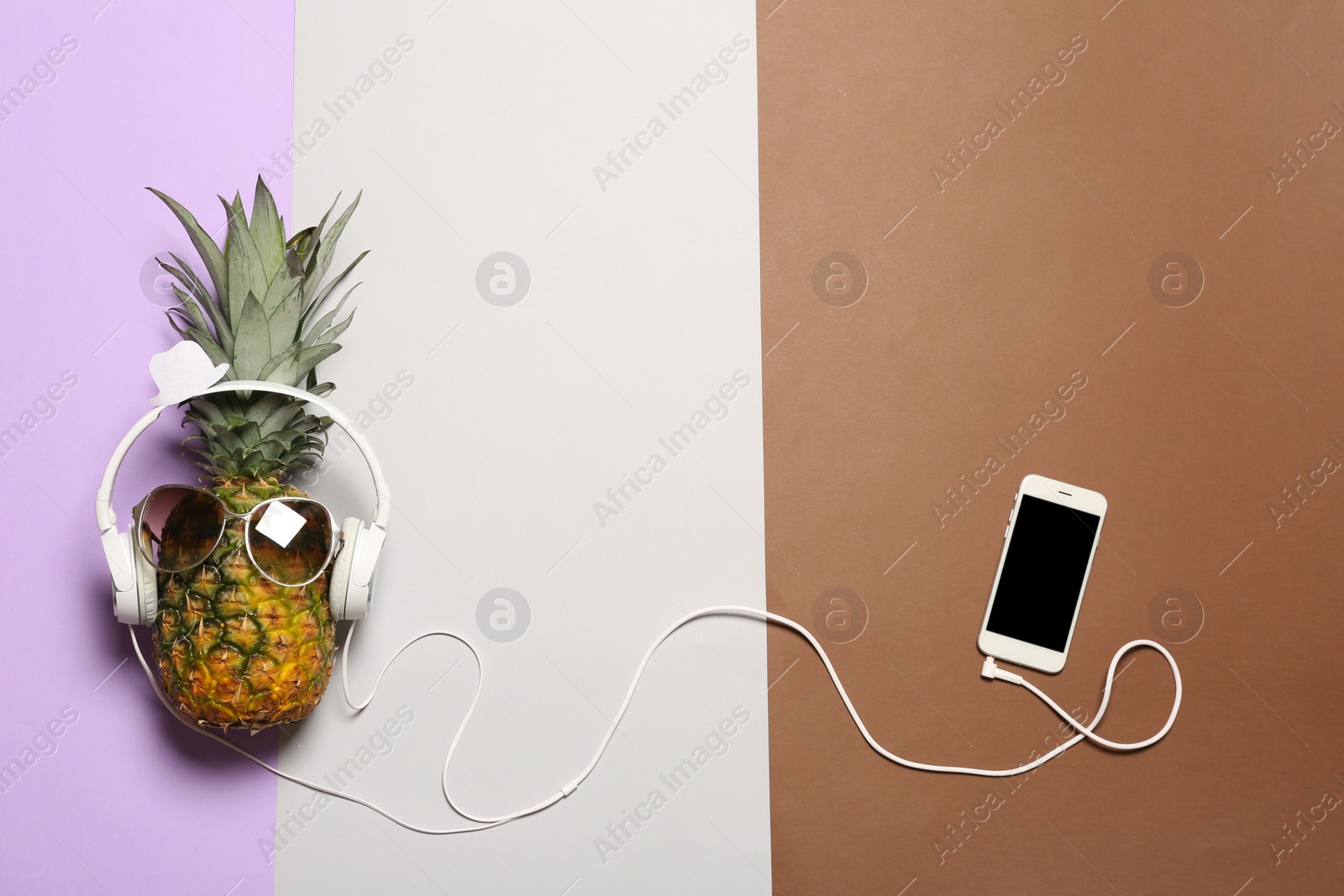 Photo of Funny pineapple with headphones, smartphone and sunglasses on color background, flat lay. Space for text