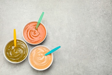 Photo of Healthy baby food in bowls on grey table, flat lay. Space for text