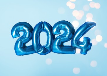Image of New 2024 Year. Bright number shaped balloons on light blue background with blurred lights