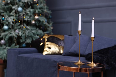 Photo of Pair of beautiful candlesticks on glass table and Christmas decor in room, space for text