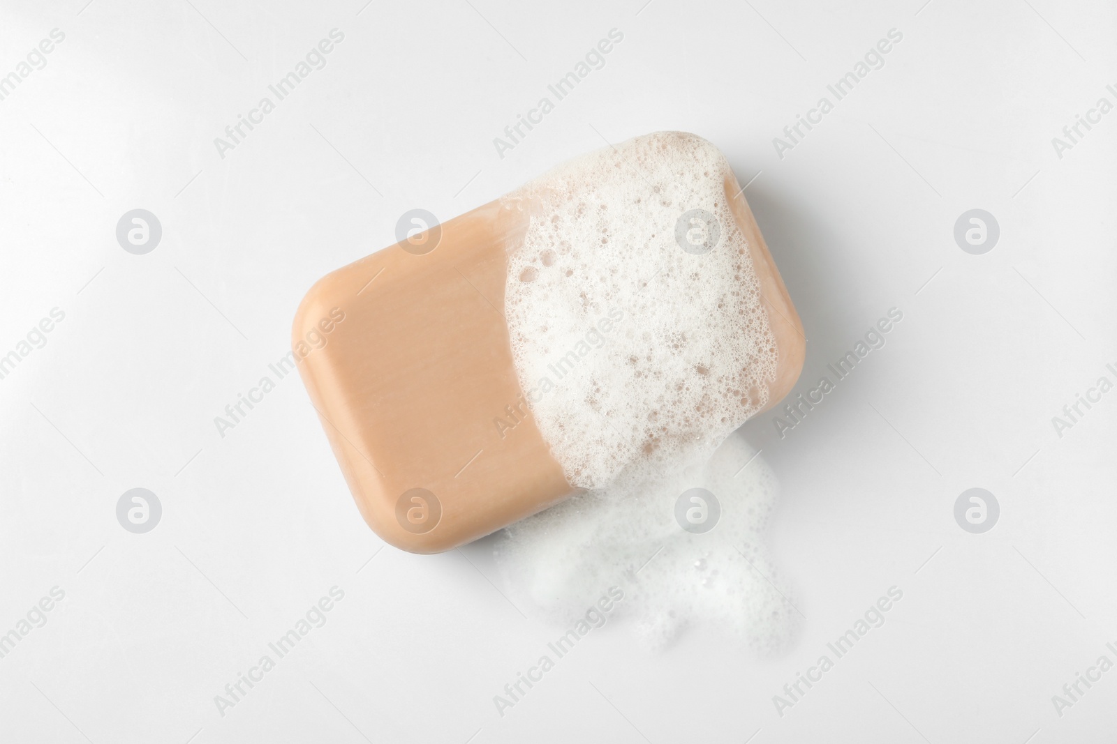 Photo of Soap with fluffy foam on white background, top view