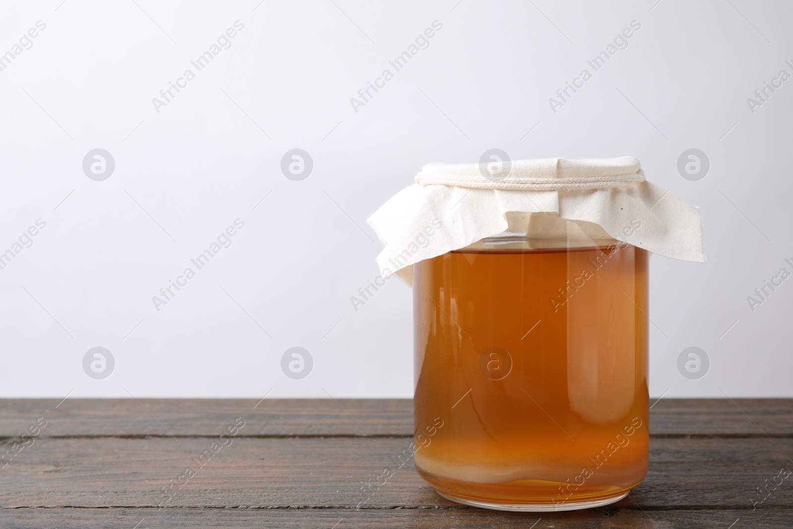 Photo of Homemade fermented kombucha in glass jar on wooden table. Space for text