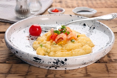 Photo of Plate with tasty shrimps and grits on table