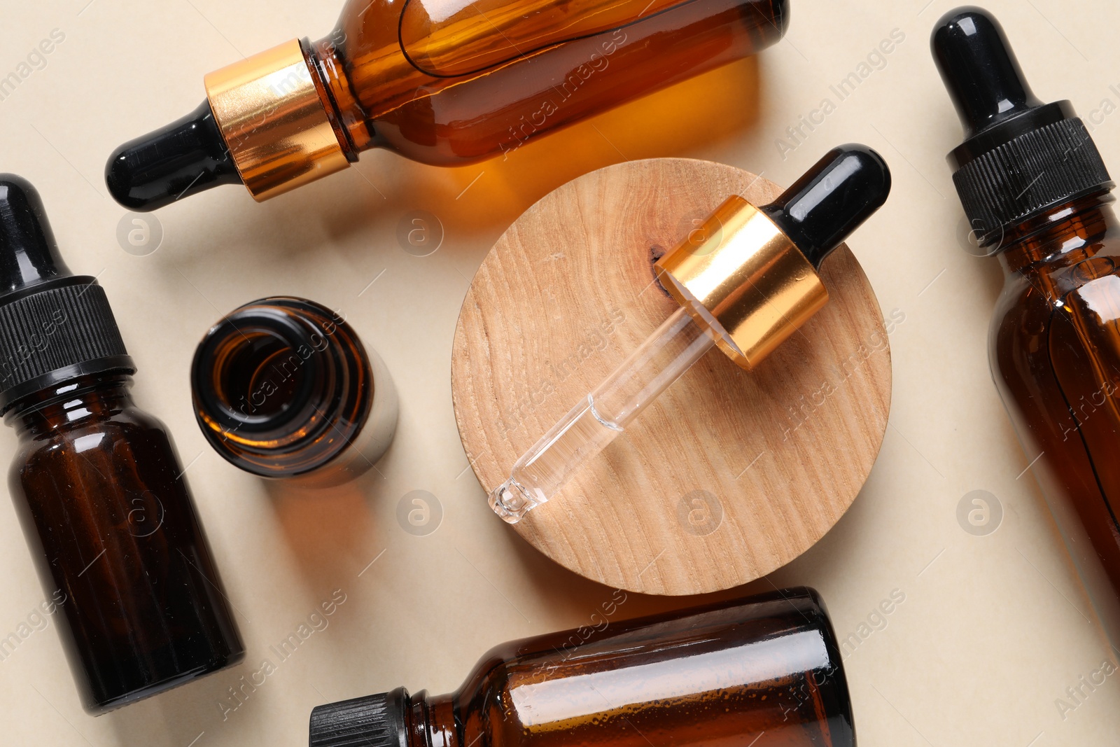 Photo of Many bottles of cosmetic serum on beige background, flat lay