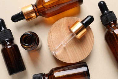 Photo of Many bottles of cosmetic serum on beige background, flat lay