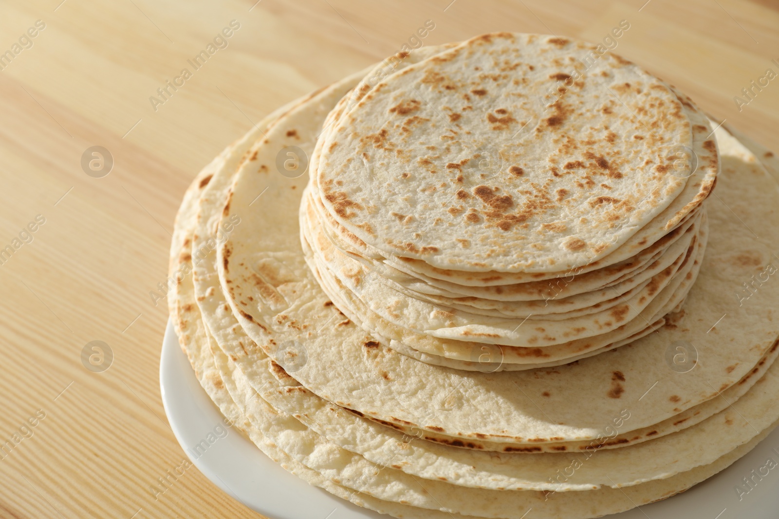 Photo of Many tasty homemade tortillas on wooden table, closeup