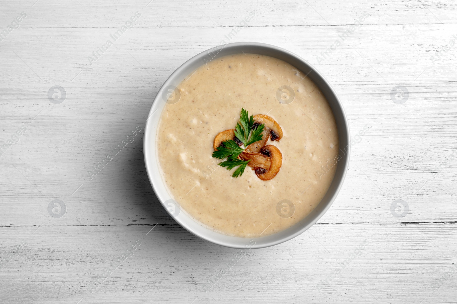 Photo of Bowl of fresh homemade mushroom soup on wooden background, top view