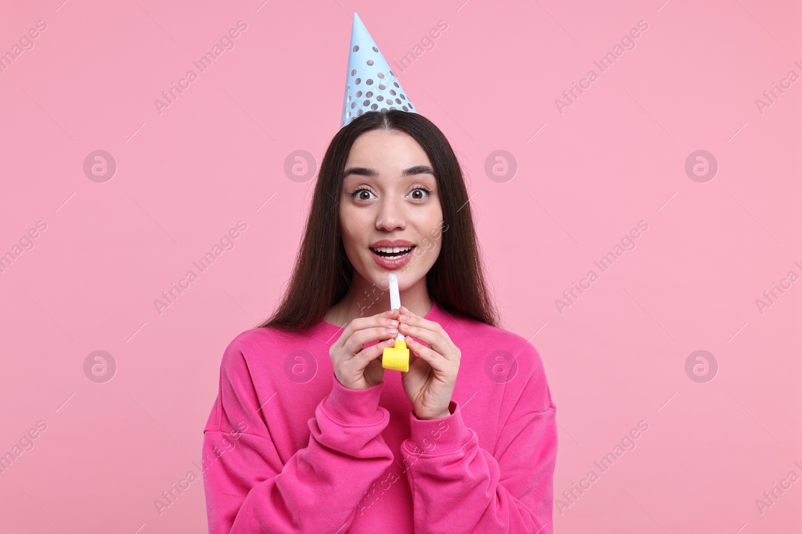 Photo of Woman in party hat with blower on pink background
