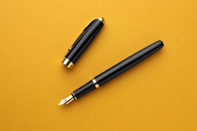 Stylish fountain pen with cap on orange background, flat lay