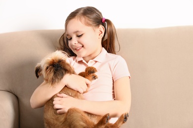 Portrait of cute girl with funny Brussels Griffon dog at home. Loyal friends