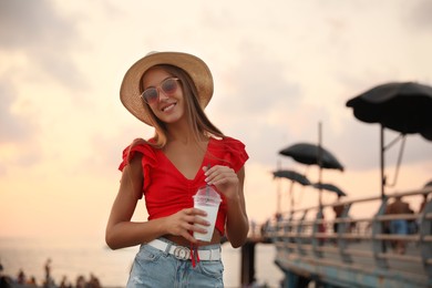 Photo of Beautiful young woman with tasty milk shake outdoors
