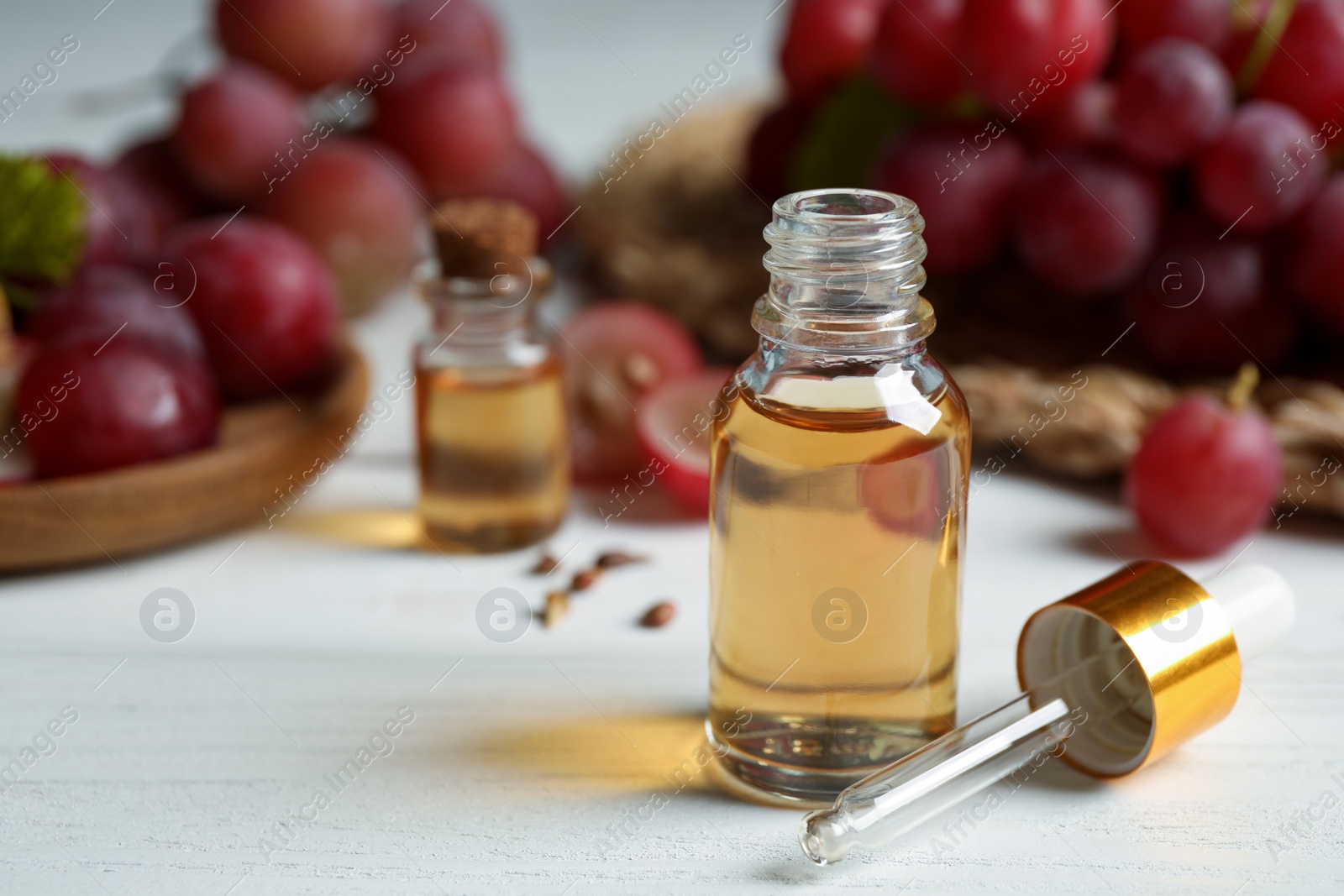 Photo of Bottle of natural grape seed oil on white wooden table. Organic cosmetic