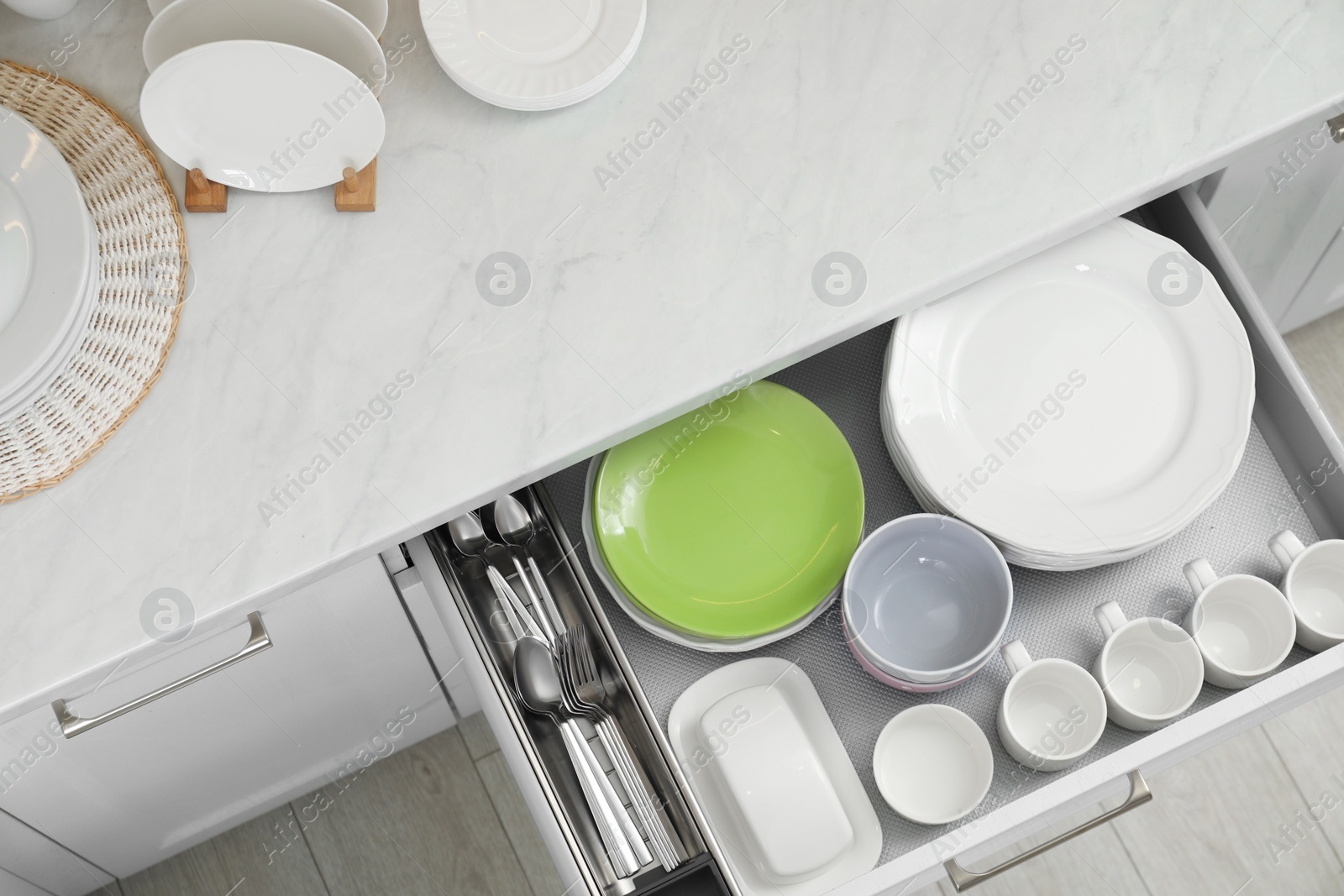 Photo of Clean plates, bowls, cutlery and cups in drawer indoors, top view