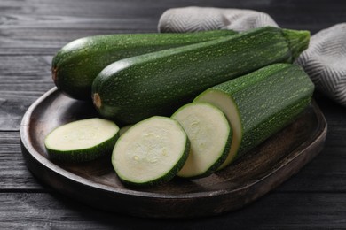 Photo of Whole and cut ripe zucchinis on black wooden table