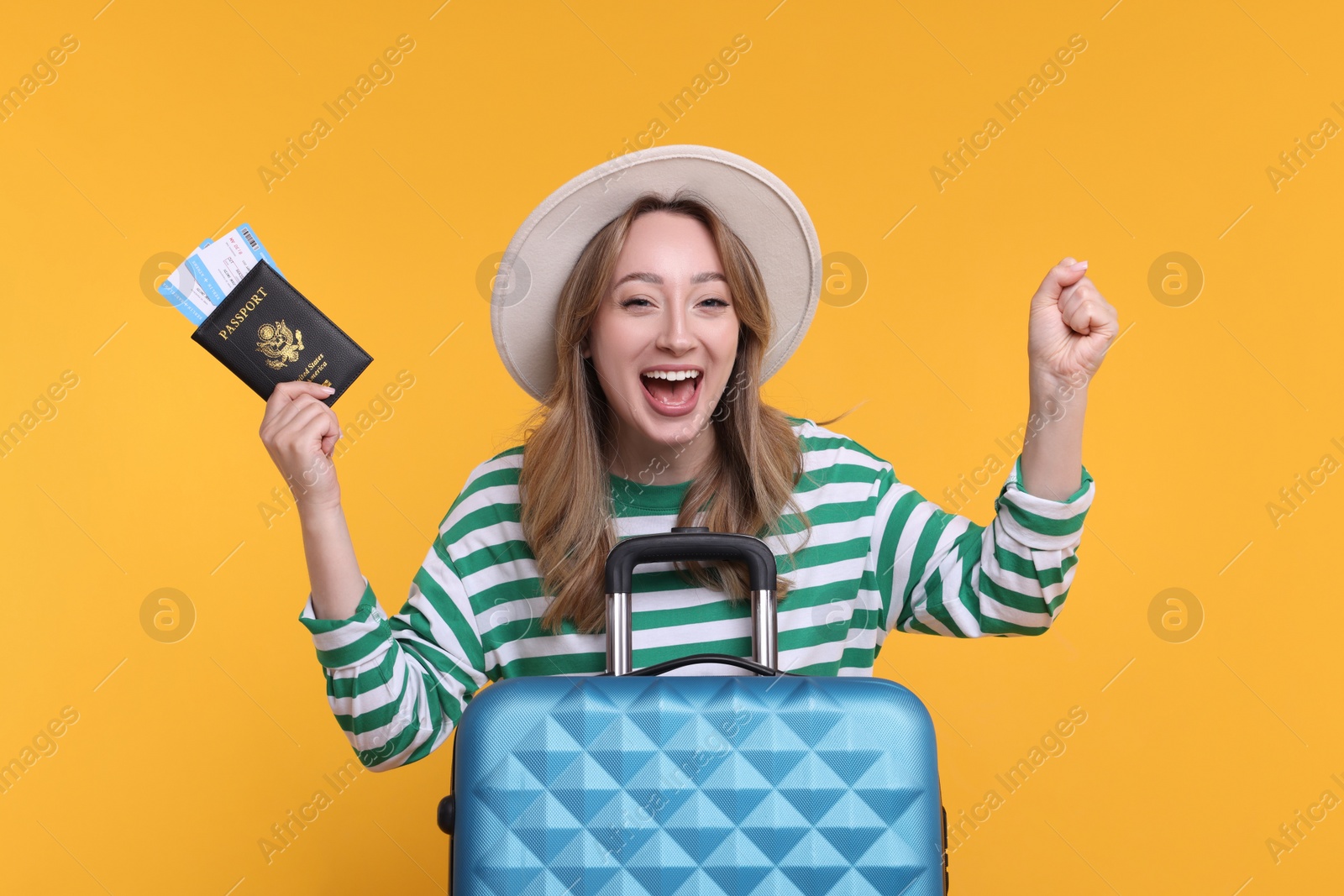 Photo of Excited young woman with passport, ticket and suitcase on yellow background