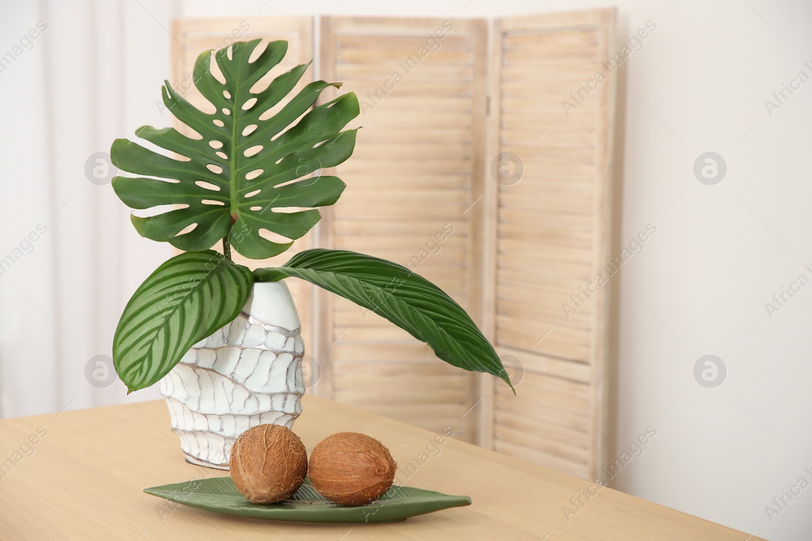 Photo of Vase with tropical leaves on table indoors. Interior design element