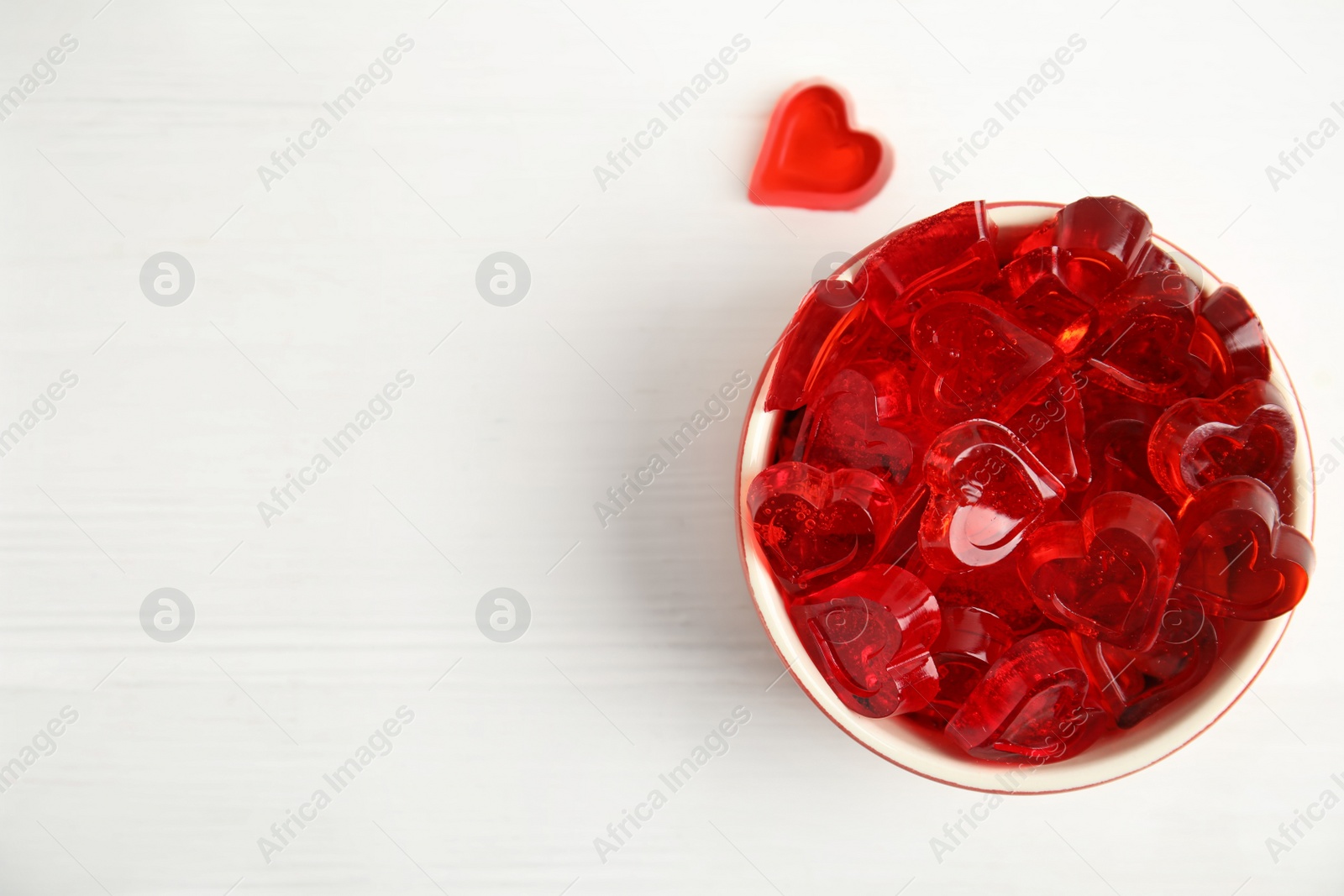 Photo of Tasty heart shaped jelly candies on white table, flat lay. Space for text